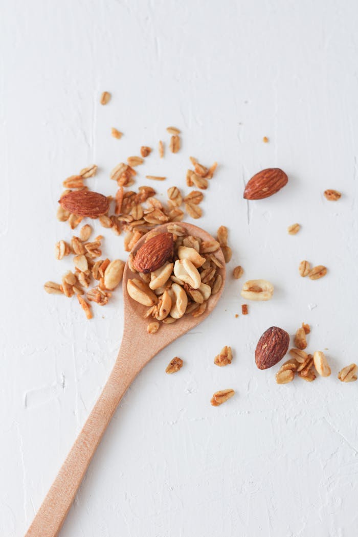 Hello world! Close-up of granola and mixed nuts on a wooden spoon over a white background, perfect for food concept.